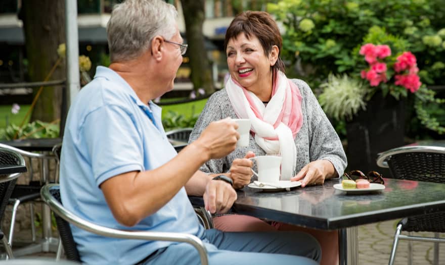 An older couple enjoying a cup of coffee outside at a café.